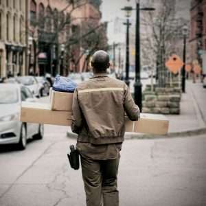 View of delivery driver holding packages while walking down city street